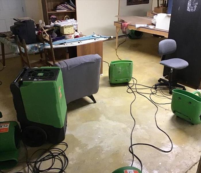 Basement with removed flooring, SERVPRO large capacity dehumidifier and air mover, placed in a circular pattern